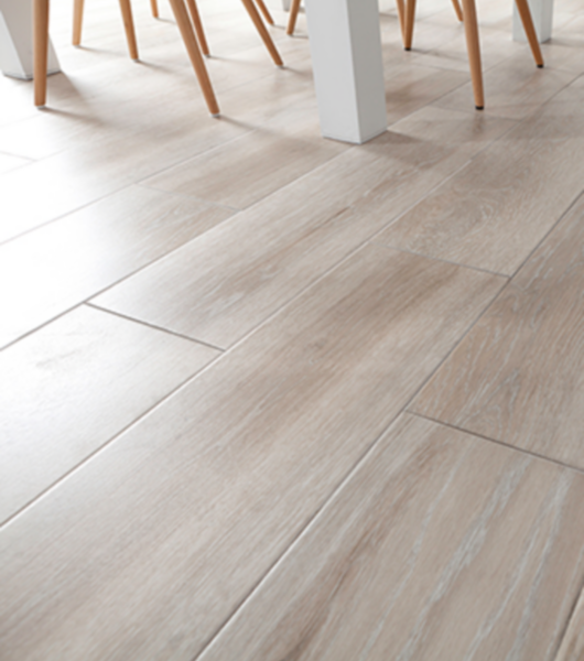 Close crop of a wood-look floor and the legs of chairs and a table.