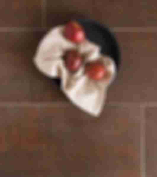 Overhead of a copper-look tile floor and a bowl of three apples.