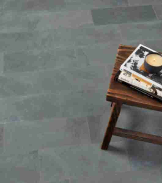 The floor of this room is covered in large, rectangular, dark grey slate tiles arranged in a staggered brick layout. Each piece of tile features unique variations in coloring, characteristic of natural stone.
