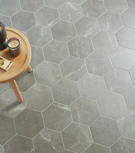 This floor features gray, hexagon-shaped porcelain tile that mimics the appearance and natural veining of genuine stone tile.