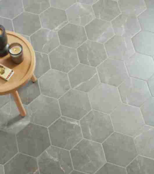 This floor features gray, hexagon-shaped porcelain tile that mimics the appearance and natural veining of genuine stone tile.