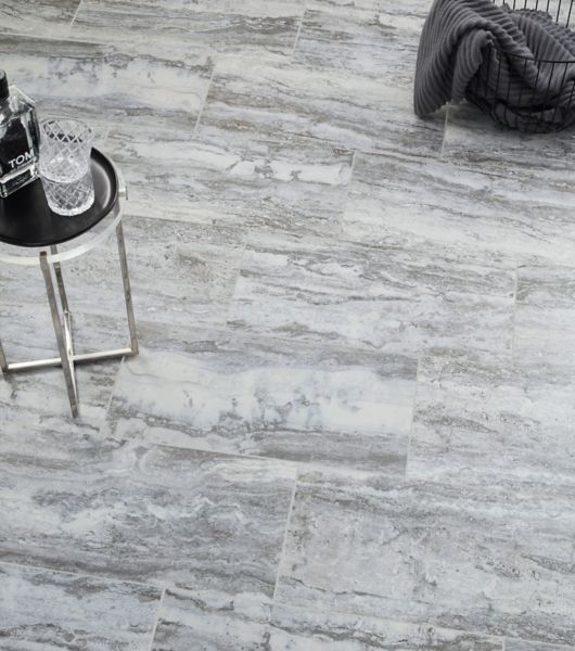 Grey stone-look tile floor with small table and glass of water.