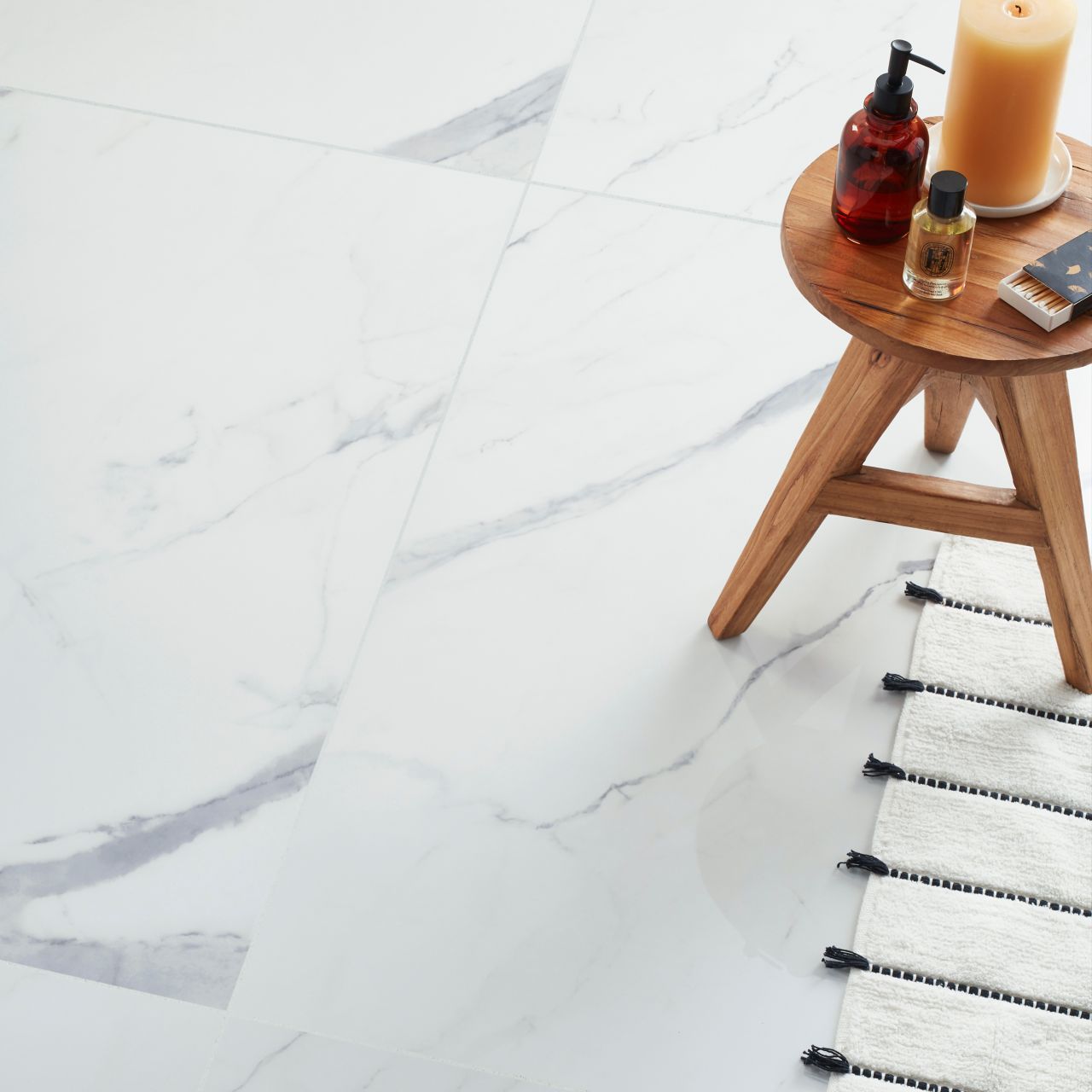 A bathroom features large-format marble-look porcelain tile all over the floors. The 48-inch square tiles mimic the appearance of white marble with light- and medium-gray veining.