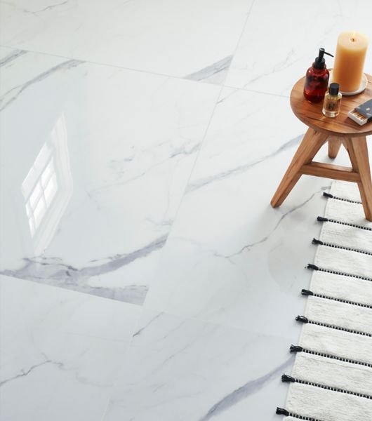 A bathroom features large-format marble-look porcelain tile all over the floors. The 48-inch square tiles mimic the appearance of white marble with light- and medium-gray veining.