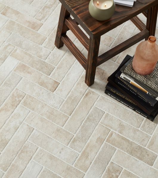 Floor featuring 3x12-inch porcelain subway tile arranged in a herringbone pattern. Arranging the light gray, brick-look tiles in this pattern creates a sense of movement that extends across the entire floor.