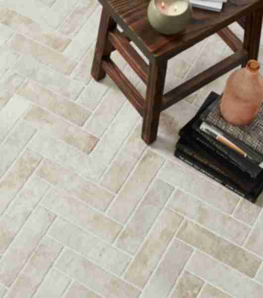 Floor featuring 3x12-inch porcelain subway tile arranged in a herringbone pattern. Arranging the light gray, brick-look tiles in this pattern creates a sense of movement that extends across the entire floor.