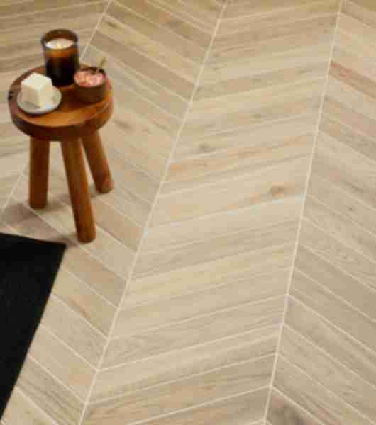 This floor is covered in light-tone, wood-look porcelain tile in chevron shapes arranged in stylish zig-zag rows.