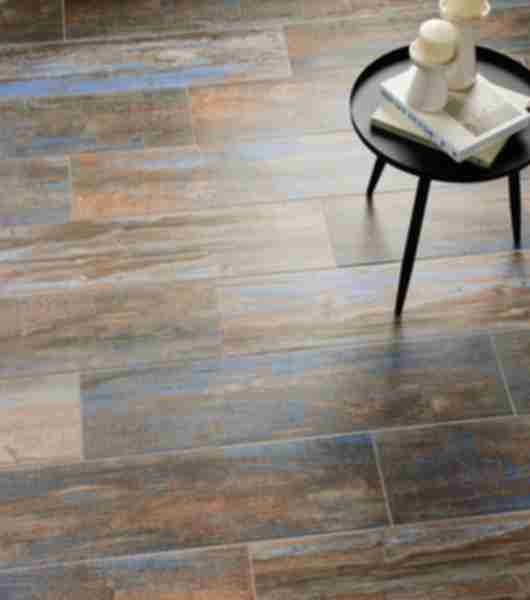 Living room with wood-look tile plank flooring arranged in offset rows. This multi-tonal porcelain floor tile includes shades of warm brown, dark bluish-gray, and light beige.
