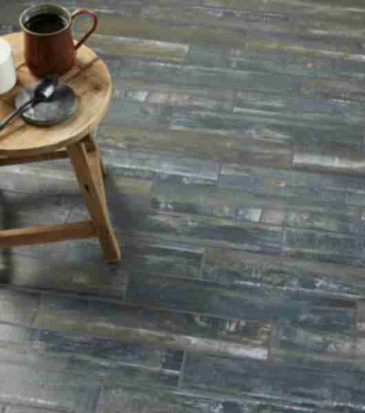 Living space with floor covered in dark wood-look plank flooring tile. Tile is multi-tonal and includes shades of gray, brown and white for a distressed look.