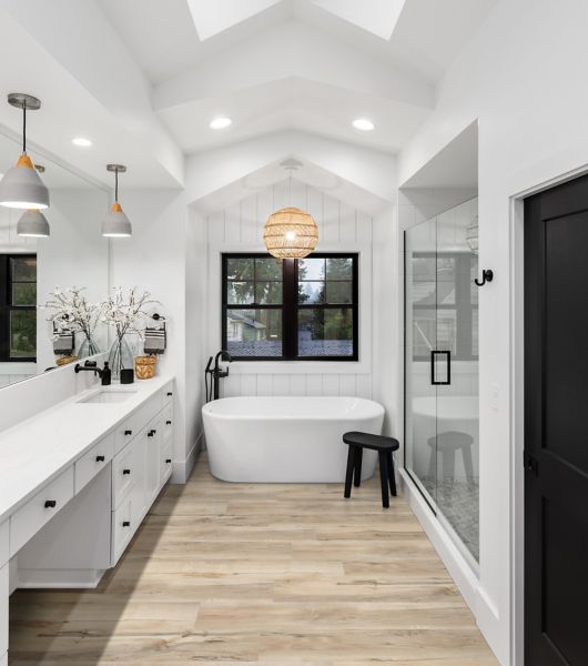 Bathroom with white tub, glass shower doors and wood-look flooring