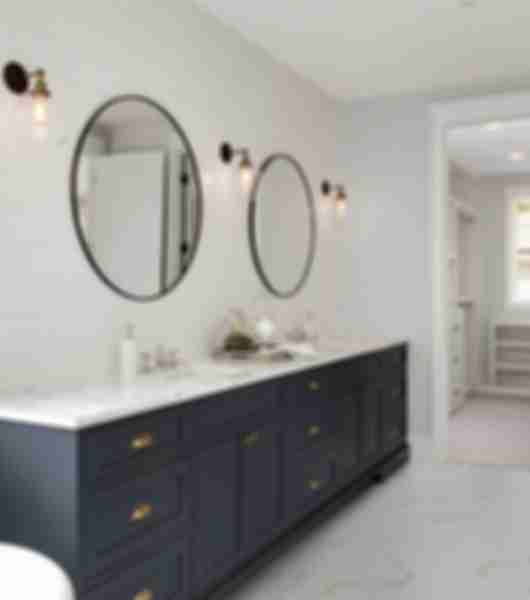 White bathroom with black double sink vanity and circular mirrors.