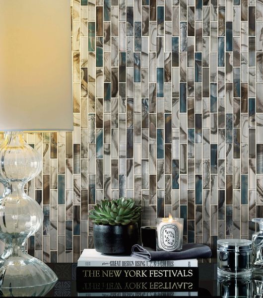 The wall behind an accent table is covered in linear glass mosaic tile that combines beachy colors like blue, green, brown and ivory. The tile is oriented vertically, creating the appearance of additional height in the space.