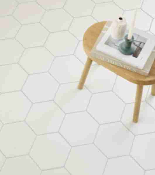 This bathroom floor is covered in white porcelain hexagon tiles installed with light gray grout.