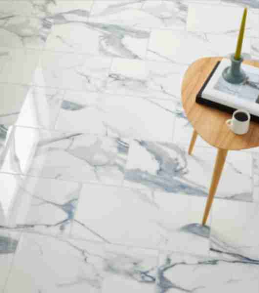 Oversized rectangular floor tiles in marble-look porcelain feature a white background, grey veining and polished finish.