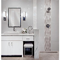 Thumbnail image of Bathroom area tiled with several different materials larger subway tiles on wall large rectangular porcelain tiles on floor making a curbless entry to the shower a partition is split with marble transition pieces accent is a waterfall in vertical glass accenting Chrome fixtures.