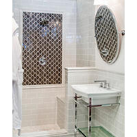 Thumbnail image of Bathroom area with four by eight subway tile on walls and wainscoting matching trim pieces used to trim out edging bench and picture frame natural stone is used to accent shower floor and curb while a textured unique hexagon is used in accent areas to create framed detail with dimension and monochromatic elements.