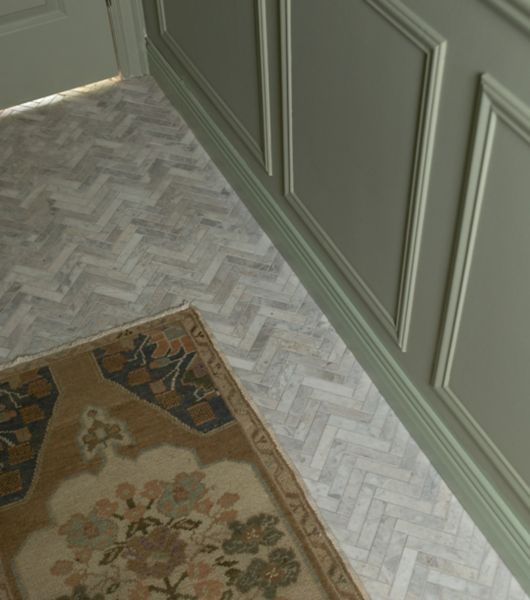 Floor covered in herringbone marble mosaic tile in shades of white, ivory and grey.