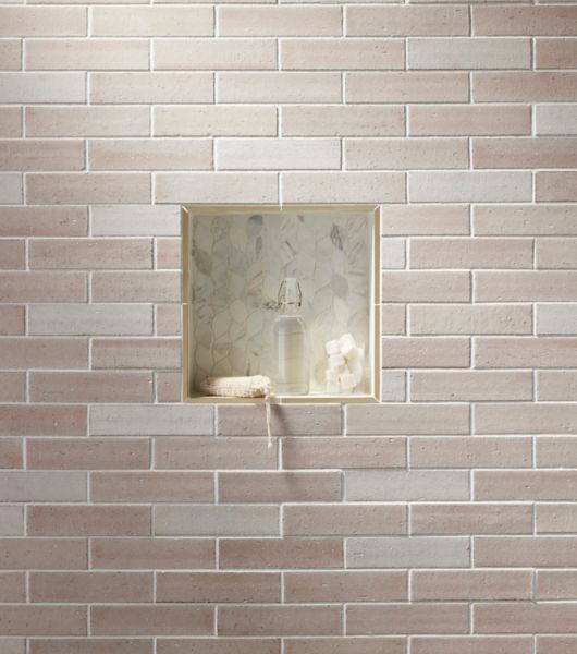 Blush-colored brick-look subway tile with marble leaf-shaped shower niche. 