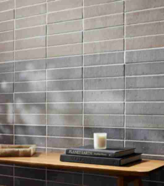 The wall of this living space features brick-look tile arranged in horizontal stacks from floor to ceiling. The same tile has been used in multiple shades of blue and installed in color-blocked sections for a gradient effect.