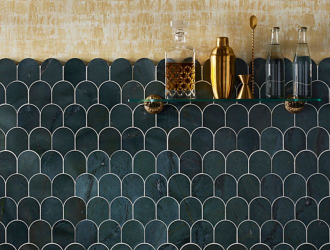 This glamorous home bar pairs gold wallpaper with a backsplash of dark green scalloped marble mosaic tile.