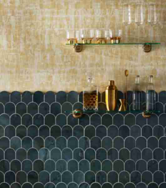 This glamorous home bar pairs gold wallpaper with a backsplash of dark green scalloped marble mosaic tile.