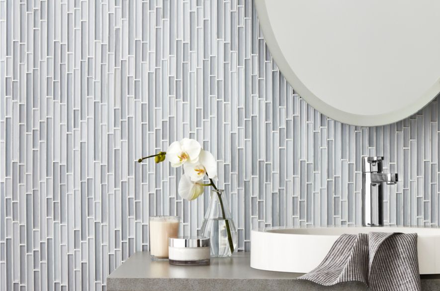 Bathroom vanity with grey and blue glass stria mosaic on wall.