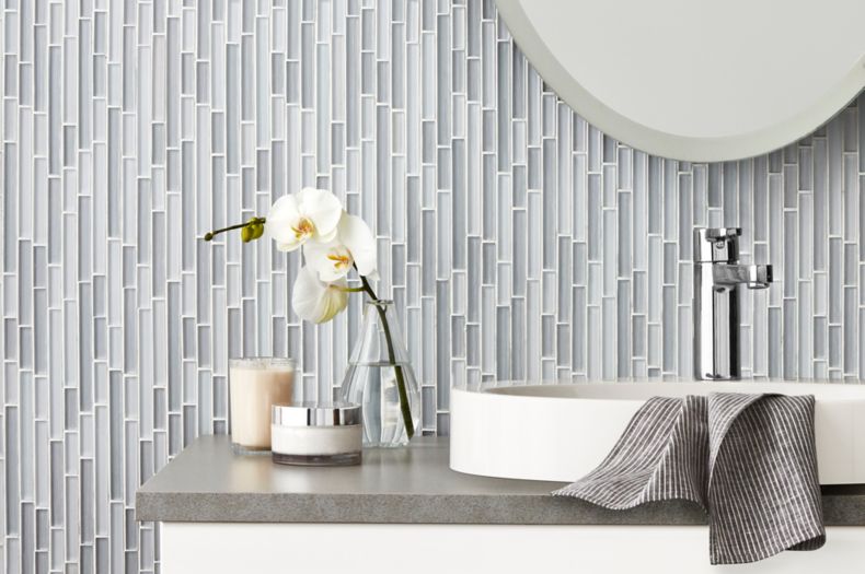 Bathroom vanity with grey and blue glass stria mosaic on wall.