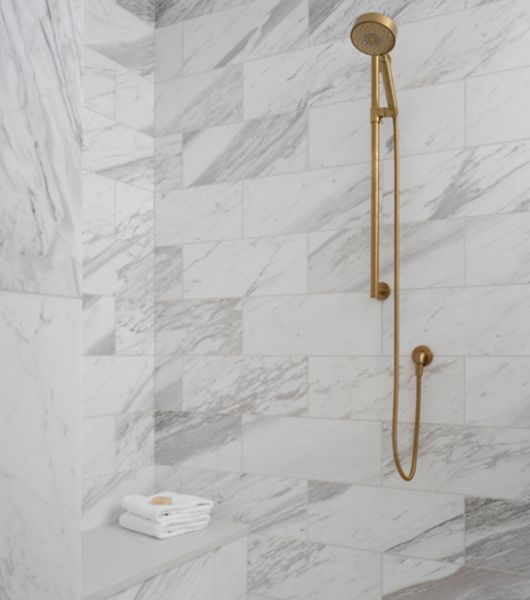 White shower with bench and gold fixtures.