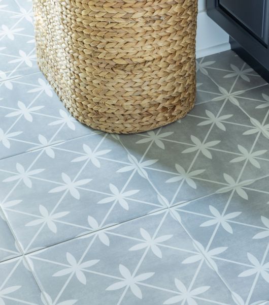 A laundry room features blue cabinets and floor covered in square ceramic tiles with a blue and white motif.