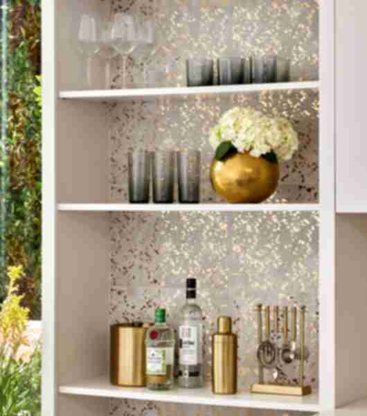 Shelf with bar elements and glasses backed with Annie Selke Goldleaf Speckle ceramic tile.