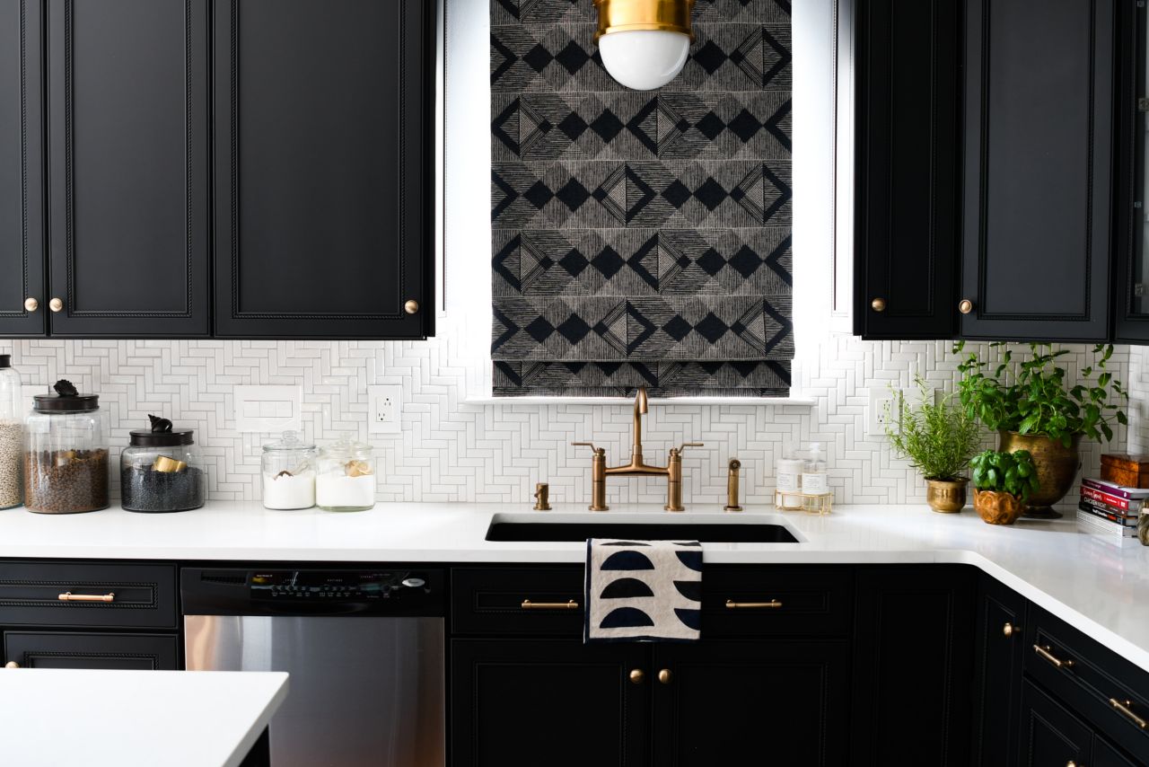 Kitchen with black counters and white herringbone patterned tile backsplash.
