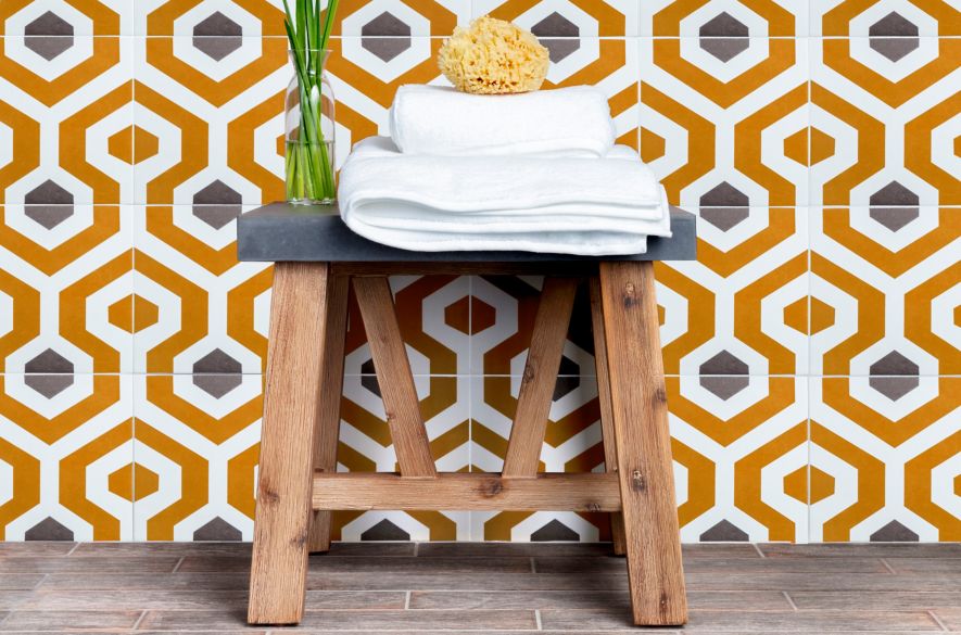 Shower wall with orange and grey geometric patterned tile.