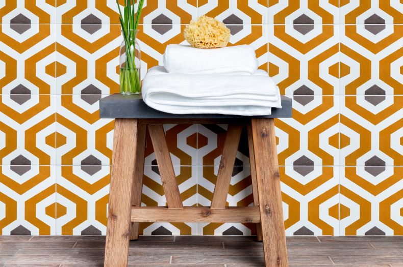 Shower wall with orange and grey geometric patterned tile.