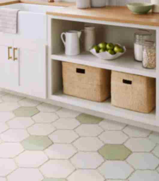 Kitchen area tiled in ceramic tile on floors and walls floor tile is a hexagon in mostly white with sage green scattered throughout while tile is 6 by 6 square tiles in a plain white and one with a lace pattern I'll have natural edges. 