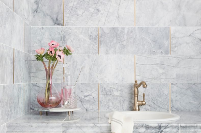 Sophisticated white and grey carrara marble wall with gold accents on kitchen backsplash.