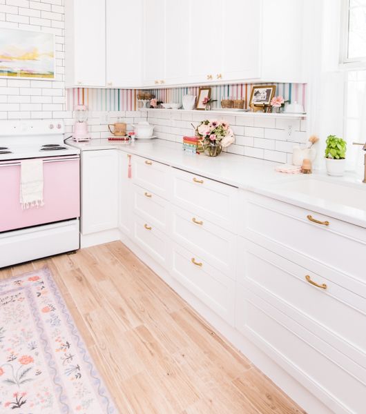 Bright, white and pale pink kitchen with wood-look tile floor.