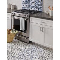 Thumbnail image of Tile kitchen area featuring a pattern tile on the floor a pattern tile as an accent behind the stove top field tile is a subway tile in white with a natural edge countertops are a slate grey cabinetry white and appliances are stainless. Coordinating tile profiles are used to divide accent from the field tile in the backsplash.