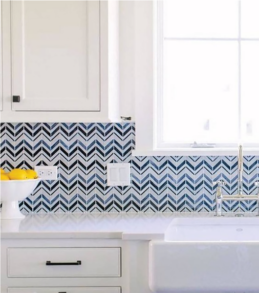 Blue zig-zag patterned tile backsplash with sink, white counters and bowl of lemons