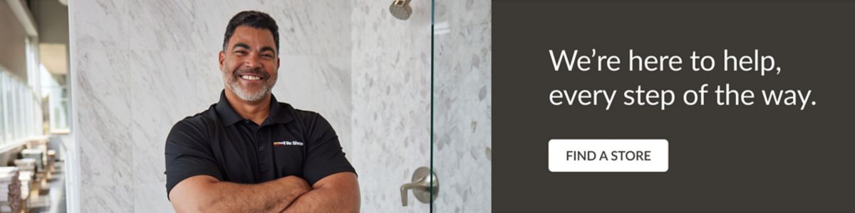 We're here to help, every step of the way.  Male sales associate smiling with folded arms in front of a marble shower display.