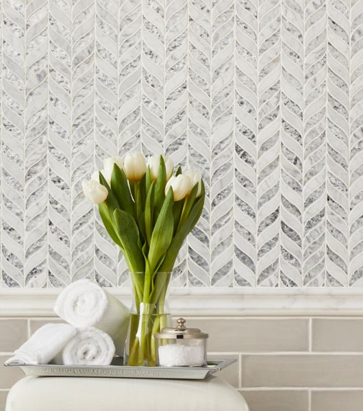 This area features a mosaic in an elegant Chevron pattern as the upper wainscoting on this wall dividing, is a marble profile chairrail and below ceramic natural edge subway tile in neutral taupe laid horizontally in a brick pattern to complete the wainscoting.