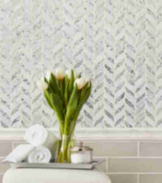 This area features a mosaic in an elegant Chevron pattern as the upper wainscoting on this wall dividing, is a marble profile chairrail and below ceramic natural edge subway tile in neutral taupe laid horizontally in a brick pattern to complete the wainscoting.