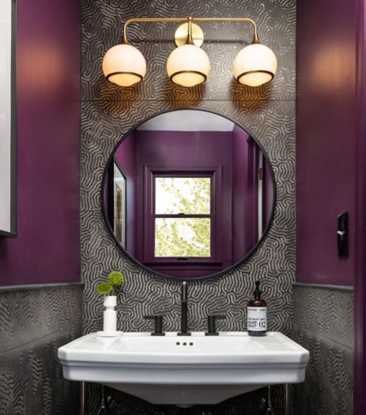 Dark purple and black and gold tile sink backsplash. White sink and circular mirror.