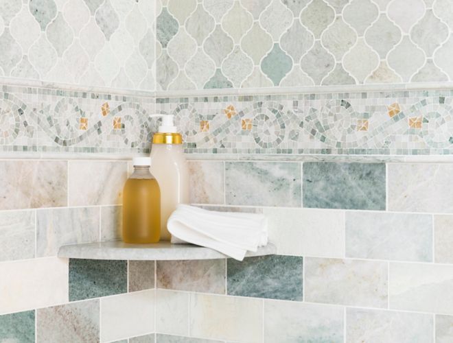 Corner of shower with green marble subway tile and mosaics on walls. 