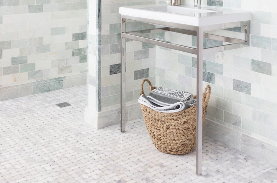 Bathroom with green marble on wall with white basketweave marble tile on floor.