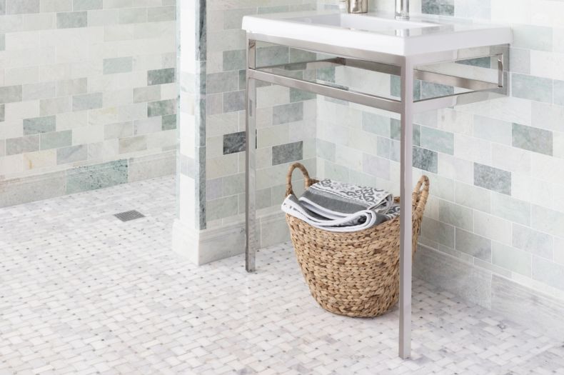 Bathroom with green marble on wall with white basketweave marble tile on floor.