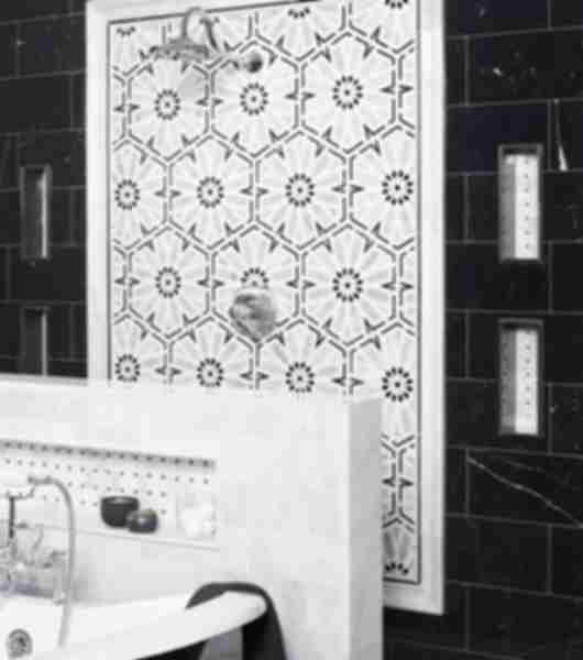 Shower with black marble wall and stone floral mosaic accent.