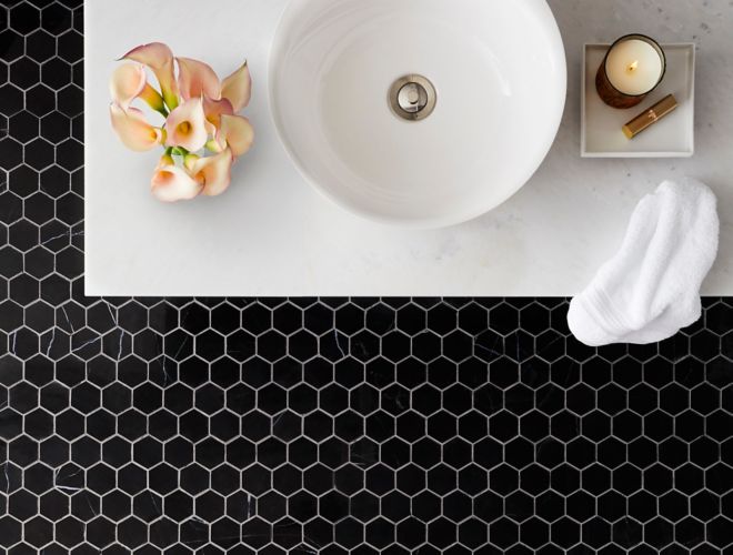 Sophisticated bathroom with black marble hexagon mosaic on floor.