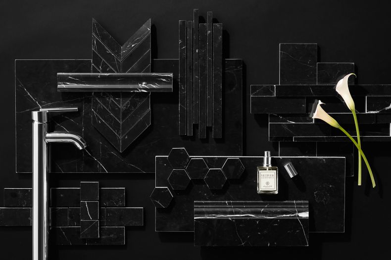 Black Marquina marble tile in various shapes and sizes with chrome faucet,  calla lily, and perfume bottle.