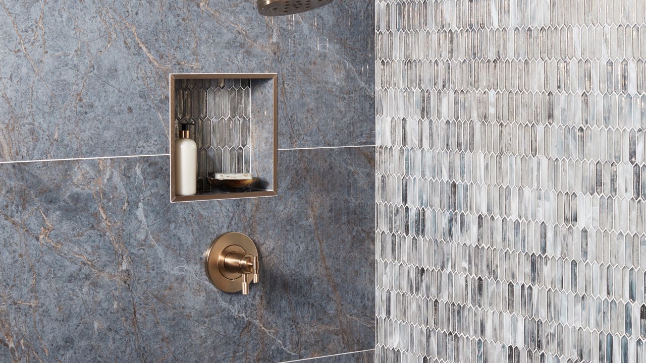 Shower with dark-blue porcelain tile with streaks of grey and brown. Silver glass mosaic accent wall.