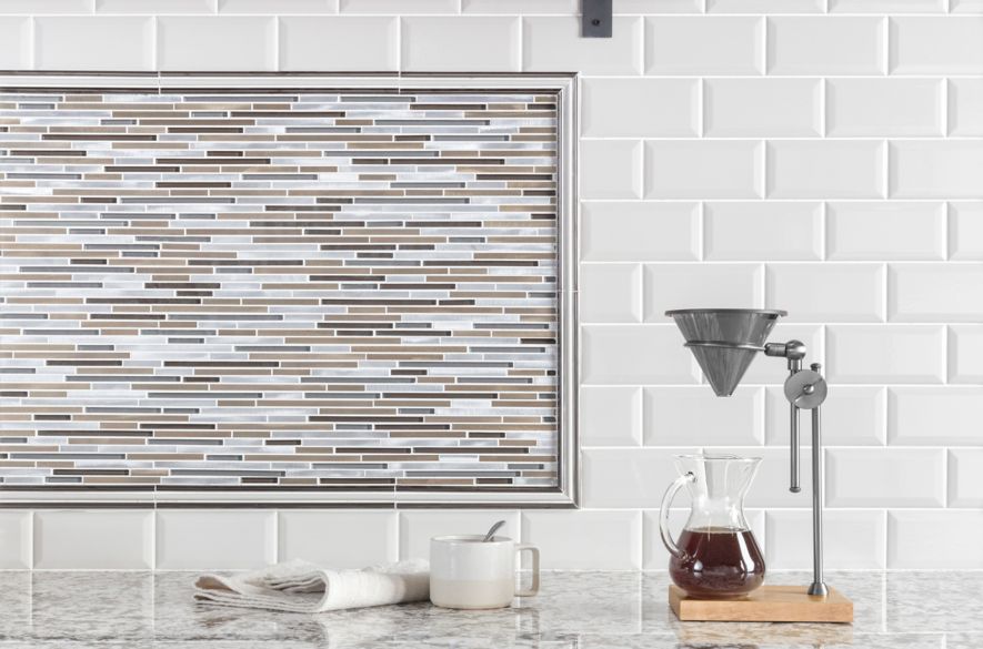 Coffee bar in kitchen with white bevel-edge subway tile and metallic stria accent tile as backsplash.